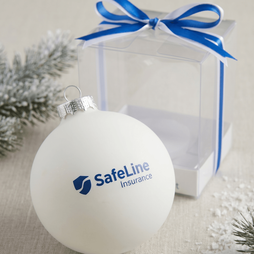 Елочный шар с логотипом SafeLine insurance, прозрачная упаковка на заднем плане